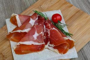 Jamon on wooden plate and wooden background photo