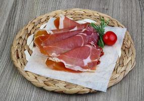 Jamon on wooden plate and wooden background photo