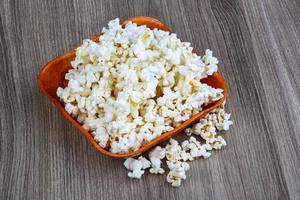 Popcorn in a bowl on wooden background photo