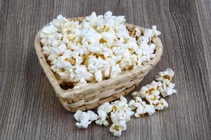 palomitas de maíz en un recipiente sobre fondo de madera foto