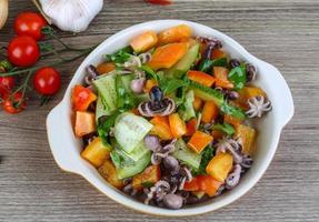 Octopus salad in a bowl on wooden background photo