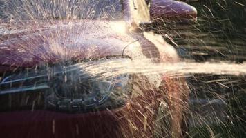 primo piano dell'acqua che scorre su un'auto mentre un lavoratore sta usando un'idropulitrice per lavare l'auto. concetto di servizio di autolavaggio. video