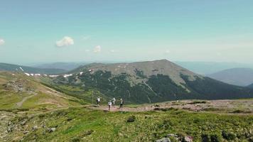 die vier Touristen, die auf dem Berggipfel stehen. in den Bergen wandern. Luftaufnahme der malerischen Karpaten. Touristengruppe, die sich auf dem Weg zum Gipfel des Berges ausruht.