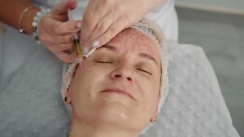 Der Arzt spritzt einer Patientin Blutplasma ins Gesicht. Behandlung mit Injektionen von plättchenreichem Blutplasma. Behandlung in einem Schönheitssalon. video