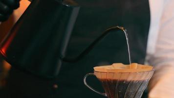 bereiding van koffie. de barista giet kokend water over de koffie en filtert deze video