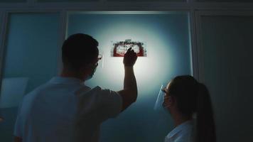 dos dentistas observan una radiografía panorámica del espacio entre dientes en una habitación oscura. video