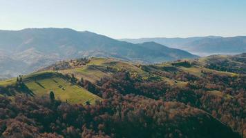 Panoramic view of scenic landscape with green forest hills and mountain peaks on sunny day. Aerial view of mountain range with meadows and forests in summer, with copy space. Concept of landscape video