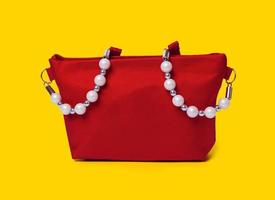 bolsa de mujer roja aislada en perlas de fondo blanco en una bolsa de cosméticos roja grande foto