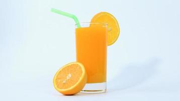 a Glass of orange juice with orange sliced in half isolated on white background with green pipe photo