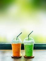 Iced green tea and Thai iced tea on wood table. photo