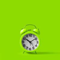 Green alarm clock on green background. photo