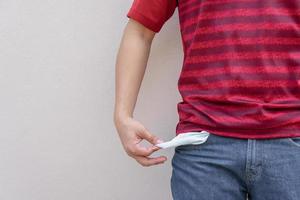 Man showing his empty pocket on wall background. photo