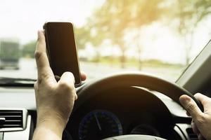 Close up of a man driving car dangerously while using mobile phone photo