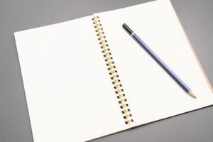 cuaderno con un lápiz. cuaderno espiral abierto en blanco con lápiz sobre fondo de escritorio blanco foto