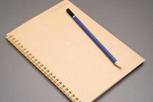 cuaderno de tapa de papel artesanal en blanco espiral cerrado con lápiz. primer plano de artículos de oficina y estudio. endecha plana foto