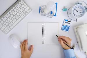 Office desk with smartphone, laptop computer, cup of coffee, and office tools. Flat lay, top view with copy space. A bank notepad and a pen are on top of an office desk table containing computer tools photo