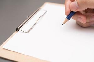 hand writing on clipboard. Stationery. write a note on empty blank with a pencil photo