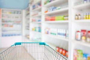 blur shelves of drugs in the pharmacy with shopping cart photo