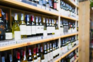 Abstract blur wine bottles on liquor alcohol shelves in supermarket background photo