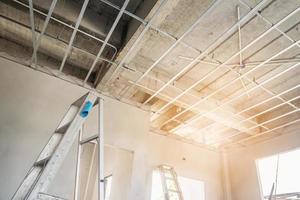 Install metal frame for plaster board ceiling at house under construction photo