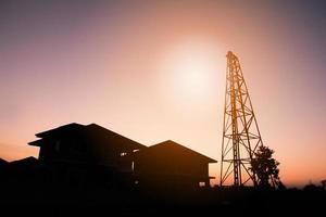 Silhouette pile driver at house building construction site with sunset sky photo