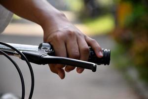 Closeup view of handlebar of bicycle which has hand of kid holding it. photo