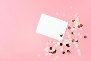 Pink confetti on pastel pink paper background. Festive holiday backdrop. Birthday congratulations Christmas New Year. Valentines Day. Flat lay, top view, copy space. photo