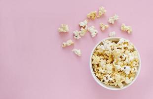 Spilled popcorn on pink background. Movie night concept. Copy space for text photo