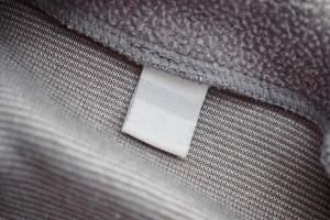 etiqueta de ropa blanca en blanco sobre fondo de textura de tela gris foto