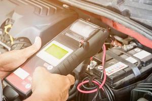 mechanic use voltmeter checking voltage of car battery in car service centre photo