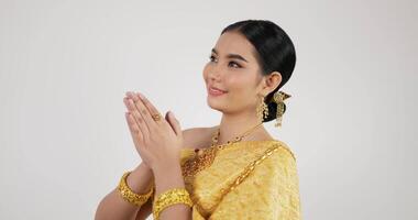 retrato de mulher tailandesa saudação de respeito em traje tradicional da tailândia. jovem fêmea olhando para a câmera e sorrindo com fundo branco isolado. video