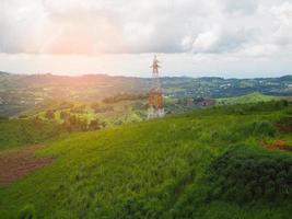High voltage power lines tower on green mountain photo