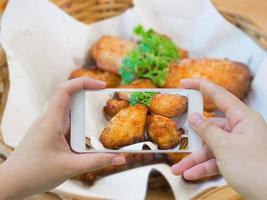 tomando fotos de alitas de pollo calientes y picantes con smartphone