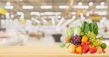 Fresh fruits and vegetables on wood table with supermarket grocery store blurred defocused background photo
