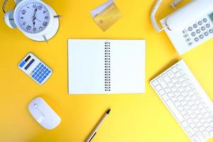 Office desk with smartphone, laptop computer, cup of coffee, and office tools. Flat lay, top view with copy space. A bank notepad and a pen are on top of an office desk table containing computer tools photo