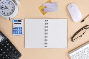 Office desk with smartphone, laptop computer, cup of coffee, and office tools. Flat lay, top view with copy space. A bank notepad and a pen are on top of an office desk table containing computer tools photo