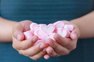 mano de mujer sostenga malvaviscos en forma de corazón para el día de san valentín foto