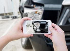 Hembra sostenga teléfono inteligente móvil fotografiando accidente automovilístico foto