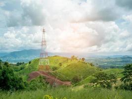 High voltage power lines tower on green mountain photo