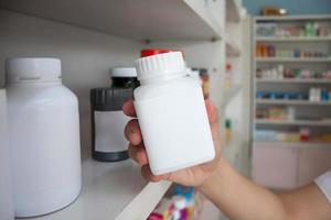 hand of woman pharmacist hold medicine bottle in the pharmacy photo