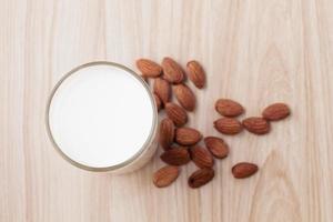 la leche de almendras en vaso con nueces está sobre fondo de madera. Enfoque selectivo. Vista superior, de arriba hacia abajo, plano. foto