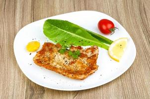 Pork schnitzel on the plate and wooden background photo