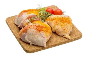 Raw chicken thigh on wooden plate and white background photo