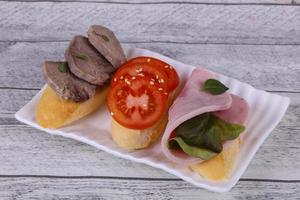 Bruschetta with tomato, ham and tongue photo