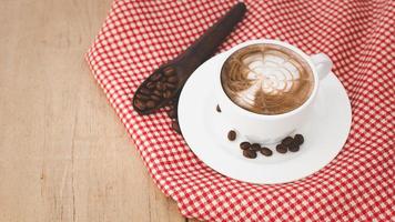 Coffee cups and coffee beans with red patterned fabric on a wooden background.copy space. photo