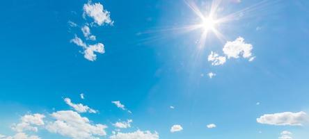 Natural abstract background of bright blue sky and fluffy white clouds on a sunny, light a flare and sun. photo