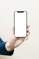 The left hand of a white woman showing a black mobile phone or cellphone and a white screen for mockup content at an isolated or cutout white background. photo