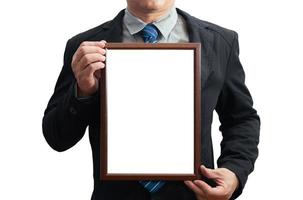 A blank diploma or a mockup certificate in the hand of a male employee wearing a black suit on white background with a clipping path.Picture frame is empty and the copy space.selective focus photo