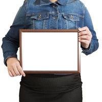 A blank diploma or a mockup certificate in the hand of a woman employee wearing a denim shirt on white background with a clipping path. The The horizontal picture frame is empty and the copy space. photo