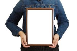 A blank diploma or a mockup certificate in the hand of a woman employee wearing a denim shirt on white background with a clipping path. The The vertical picture frame is empty and the copy space. sele photo